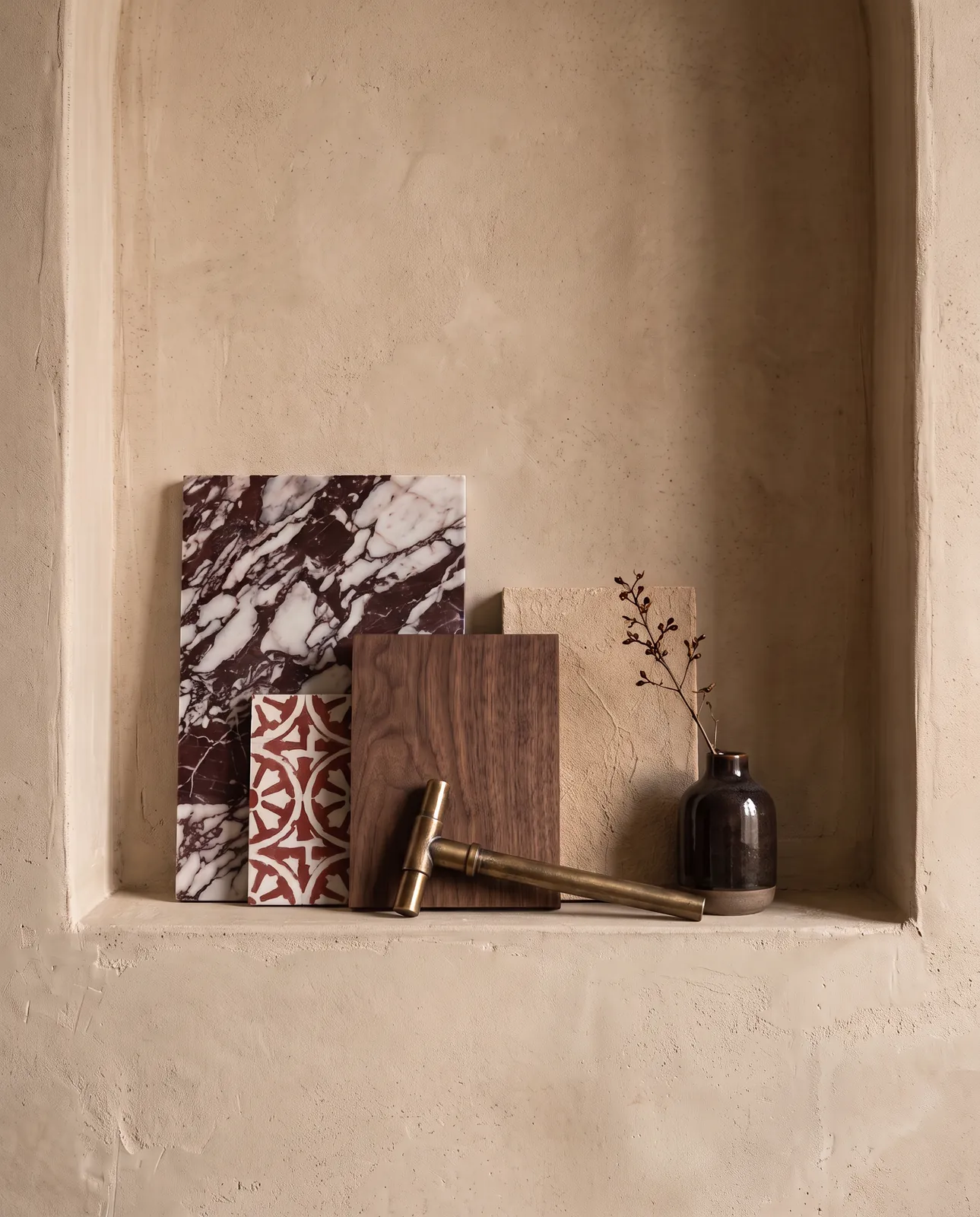 Oxblood marble, walnut and brass samples on a plaster ledge